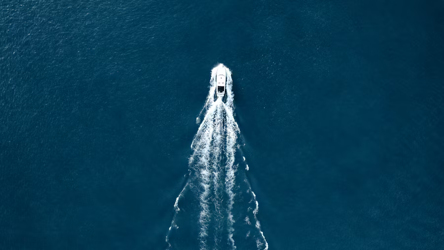 birdseye view of a boat on a body of water with a trail of wake