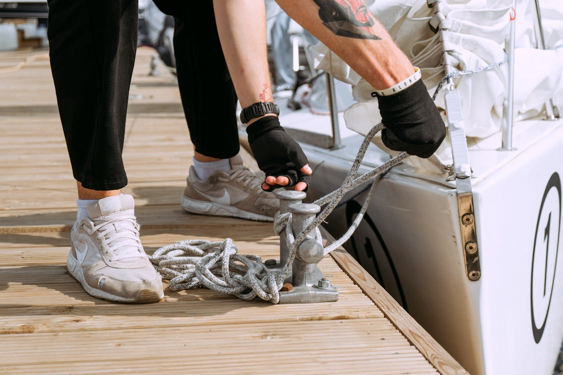picture of a person from the knees down tying off a boat on a dock