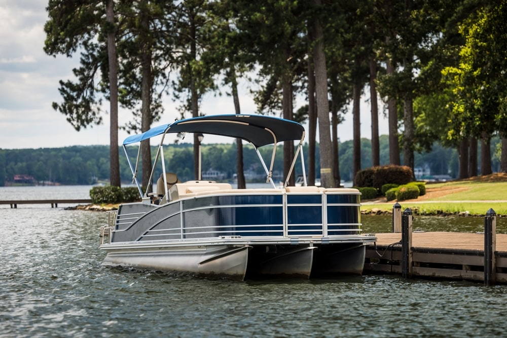 pontoon boat docked shoreside on a lake