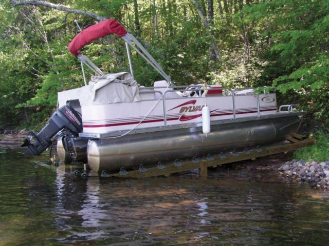 white pontoon with red trim resting on a ShoreDocker dock on a lake shoreline